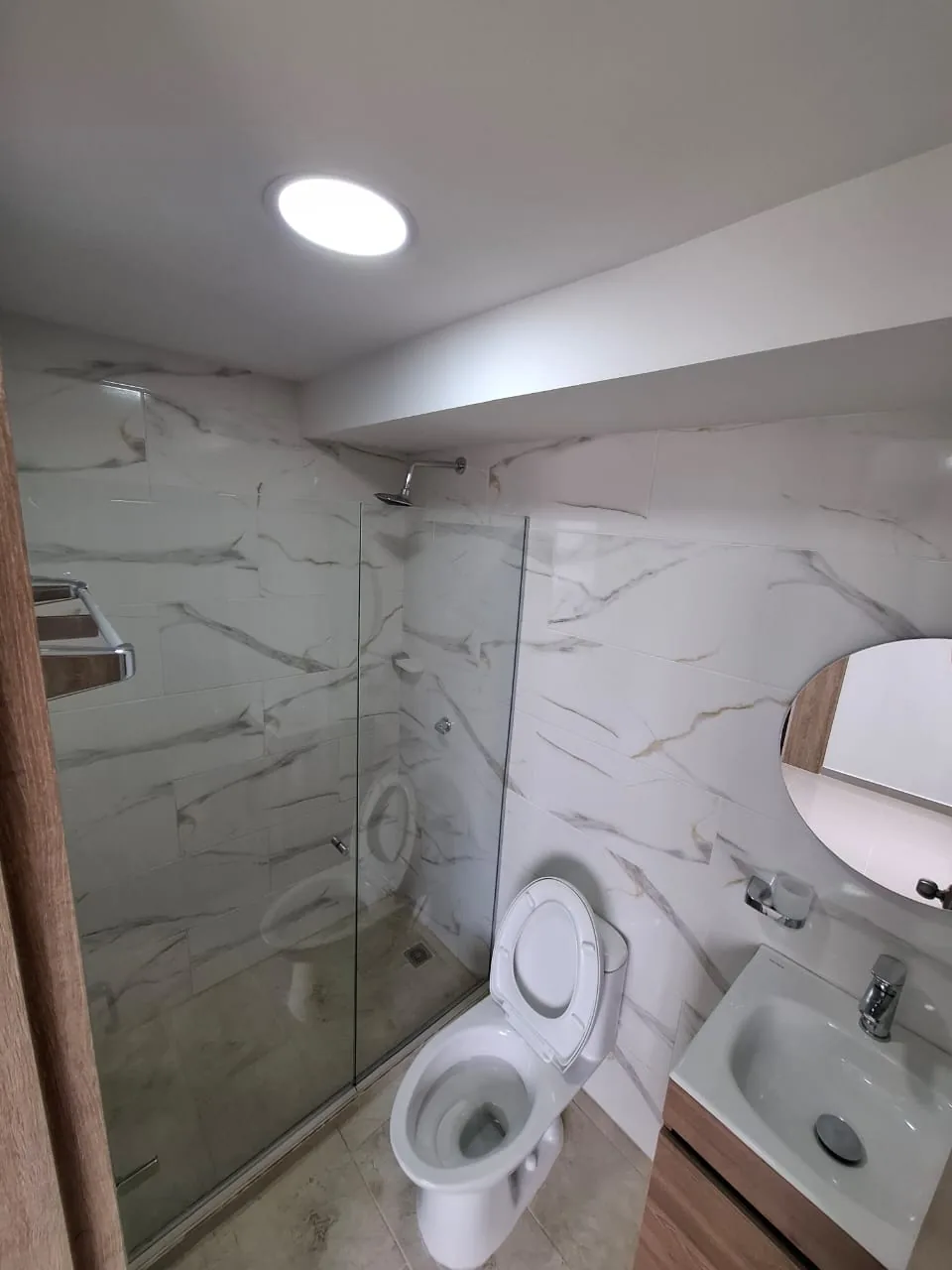 Baño con enchape en mármol blanco y ducha a nivel